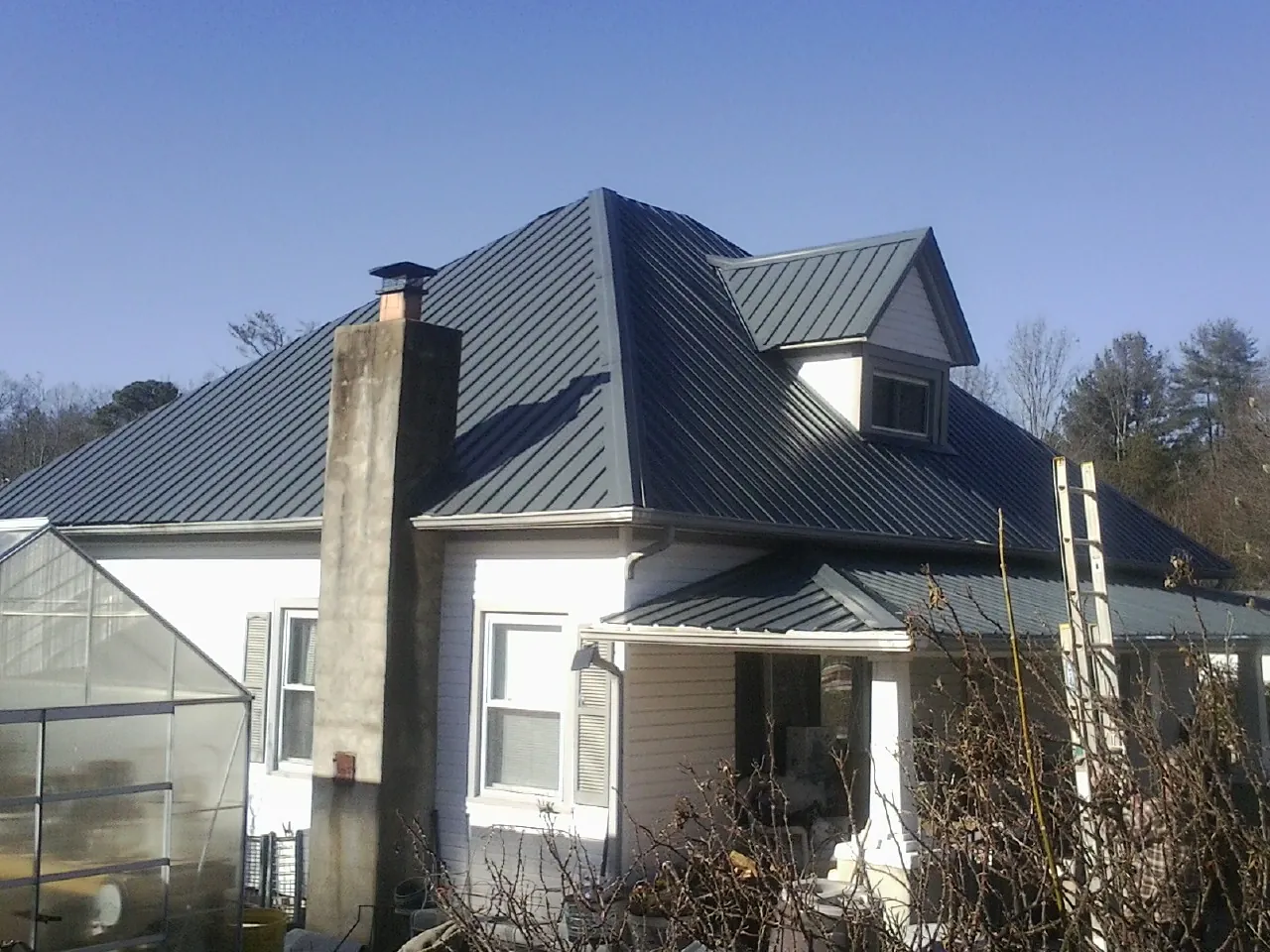 Dark blue standing seam metal roof on a white farmhouse with dormer — Slate & Tile Roof Repair by Roofing Brothers in Von Ormy